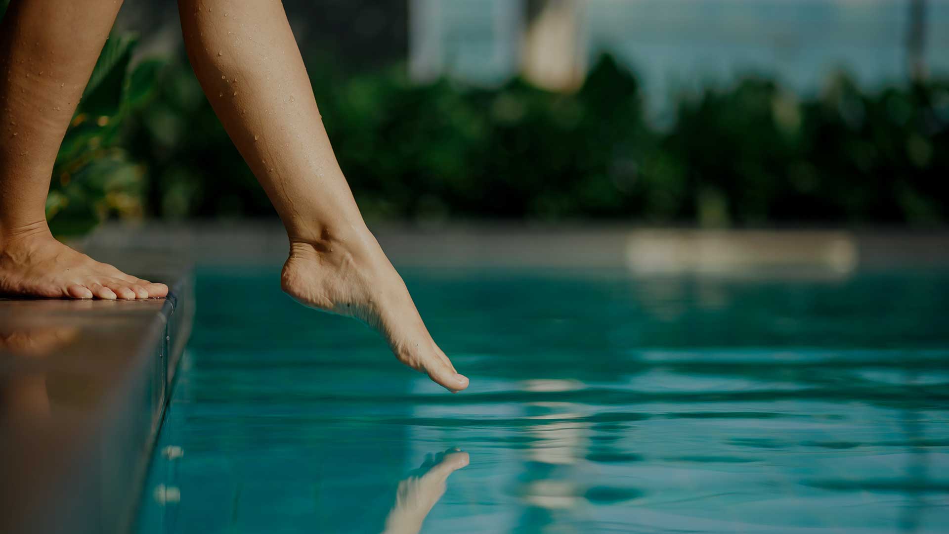 Pie d'une femme touchant la surface de l'eau limpide d'un bassin.